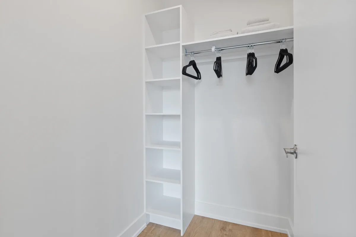 A finished Florida walk-in closet with LED shelf lighting, a center island, and a ventilated, moisture-tolerant system
