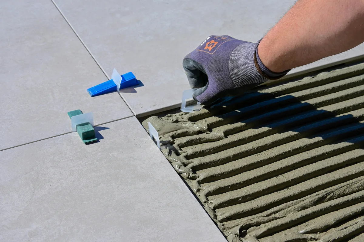 A 10-foot straightedge laid across a leveled Florida slab with a feeler gauge measuring the gap for flatness tolerance