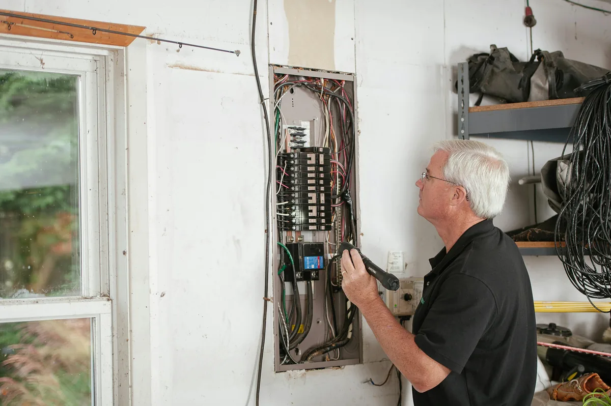 Installer mounting a damp-rated recessed LED fixture over a Florida kitchen sink