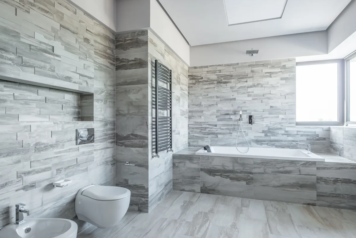 Installer setting slip-rated porcelain floor tile in a Florida bathroom with mold-resistant grout