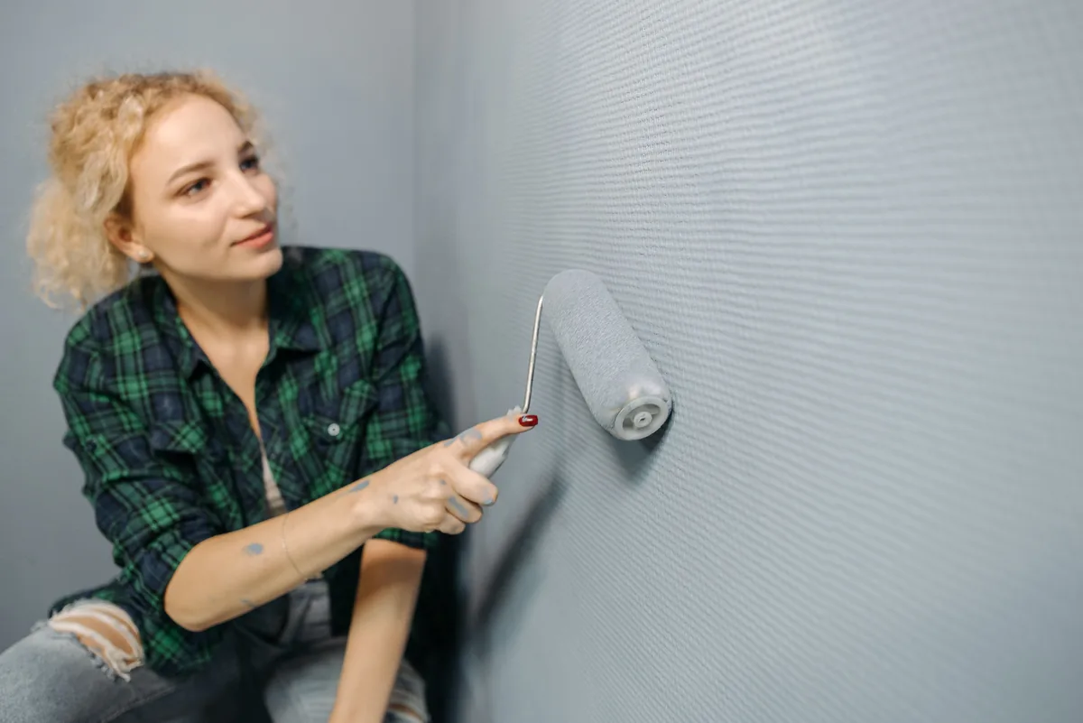 Painter prepping and stain-blocking a Florida wall before applying mildew-resistant acrylic
